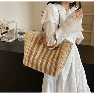 Close-up of woven straw texture and premium brown leather handle on striped beach tote bag
