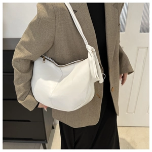 Detail of white PU leather crescent bag featuring a stylish knotted shoulder strap and zipper