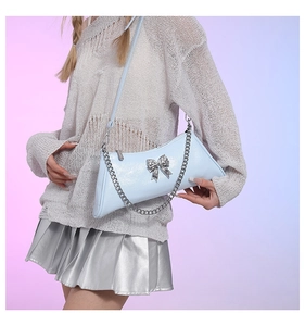 Detail of light blue PU leather shoulder bag featuring silver bow and chain strap