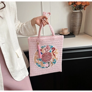 Detailed close-up of pink woven straw handbag with traditional Chinese dragon embroidery