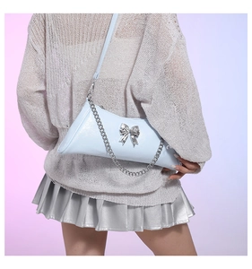 Detail of light blue leather crossbody bag with silver bow buckle worn by model
