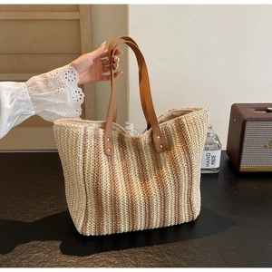 Detail of hand-woven straw tote with brown leather handles and striped texture