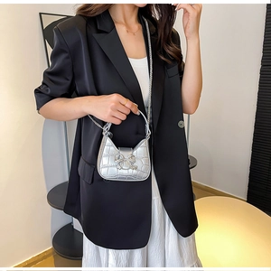 Detail view of silver PU leather crossbody bag with crocodile pattern and rhinestone bow
