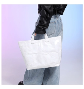 Detailed view of white Tyvek tote bag with embossed lettering and wrinkled texture