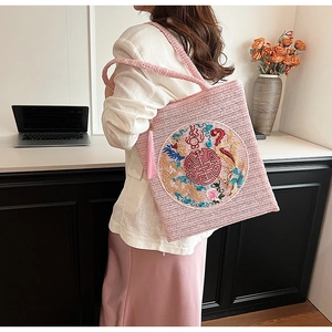 Detail of pink straw tote bag featuring traditional dragon and phoenix embroidery