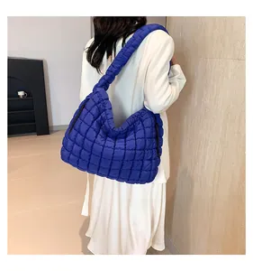 Detail of royal blue quilted cloud bag on shoulder with thick padded strap texture