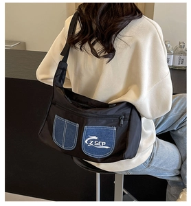 Detail view of denim pockets with ZSCP logo on black nylon crossbody bag