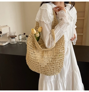 Detail of a beige straw hobo bag with hollow mesh weave and a yellow tulip flower