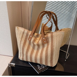 Detail of the woven vertical stripe pattern and brown leather handles on this beach tote bag