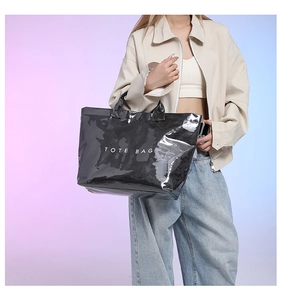Detail of glossy black Tyvek tote bag showing its reflective texture on a model