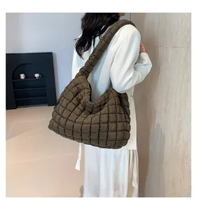 Macro detail of the oversized olive green quilted puffer tote bag with side ties