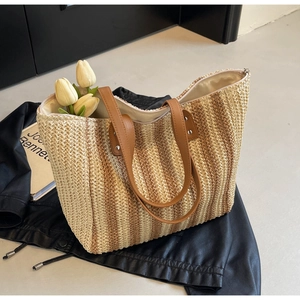 Detail of striped woven beach tote bag with leather handles and metallic rivets