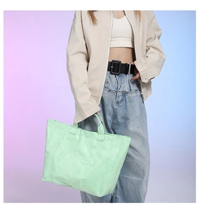 Detail of mint green tote bag with crinkled texture and embossed TOTE BAG text