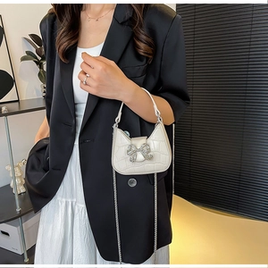 Close-up of white crocodile pattern crescent bag with a sparkling diamond butterfly buckle