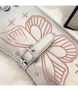 Dettaglio di stivali in pelle PU argento con ricami a farfalla rosa e borchie metalliche
