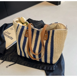 Detail of blue and beige striped straw tote with leather handles and interior zipper pocket