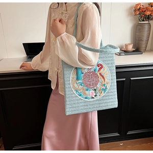 Detail of light blue woven handbag with dragon phoenix embroidery and red Xi character