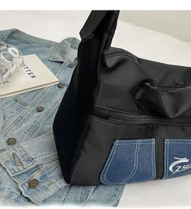 Detail of black nylon crossbody bag featuring denim pocket and white brand logo