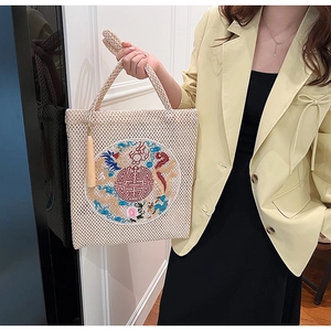Detail of straw woven handbag with traditional Chinese embroidery and tassel accents