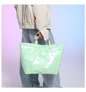 Close-up of mint green Tyvek tote bag with white TOTE BAG print and wrinkled texture