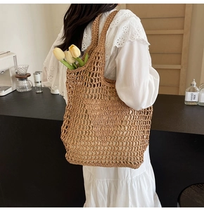Detail shot of a brown woven straw tote bag featuring an open-knit crochet mesh design