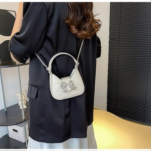 Detail of off-white crocodile embossed PU leather handbag with rhinestone bow buckle