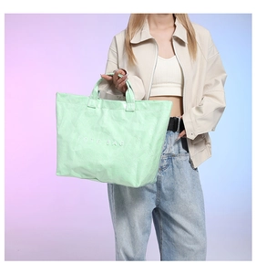Detail of mint green Tyvek tote bag with white TOTE BAG text and crinkled texture