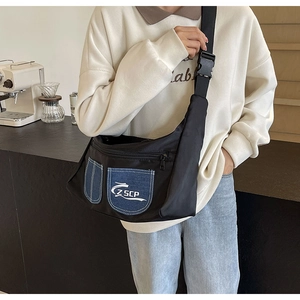 Close-up of black nylon crossbody bag with blue denim pockets and wide strap details