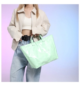 Detail view of mint green glossy tote bag with TOTE BAG lettering and reflective finish