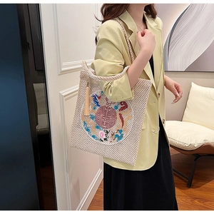 Detailed view of woven tote bag featuring Chinese dragon embroidery and yellow silk tassel