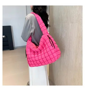 Detailed side view of a large rose pink quilted puffer tote bag with integrated wide strap