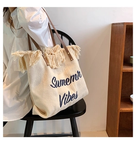 Détail d'un sac cabas tissé beige avec bord à franges et broderie Summer Vibes