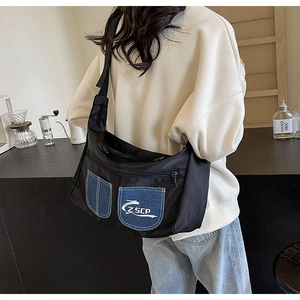 Detail of black nylon crossbody bag with denim patchwork pockets and wide shoulder strap