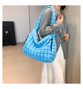 Detailed side view of large blue quilted puffer cloud bag with plush shoulder strap