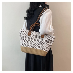 Close-up of woven checkered tote bag featuring brown leather handles and khaki base