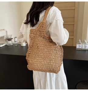 Detailed macro view of the beige hand-woven straw tote bag with mesh hollow texture