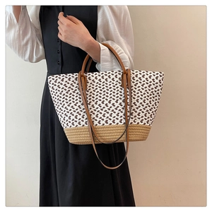 Detail shot of woven tote bag with brown leather handles and adjustable shoulder strap