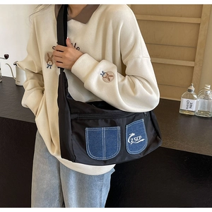 Detail shot of black nylon crossbody bag with blue denim pockets and adjustable strap