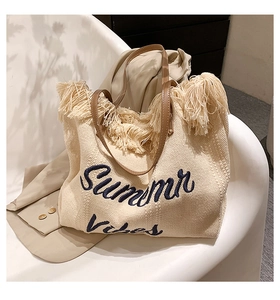 Gros plan détaillé du sac cabas en paille tissée avec broderie et bordure à franges