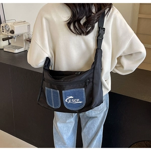 Close-up of black nylon crossbody bag featuring denim pockets and adjustable buckle strap