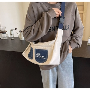 Detailed shot of the cream canvas crossbody bag with blue denim pocket and wide nylon strap