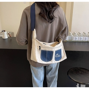 Close-up of beige canvas crossbody bag with denim pockets and adjustable blue strap