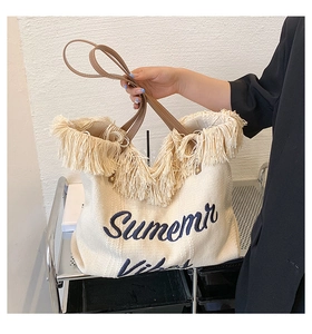 Détail du sac cabas bohème en paille tressée avec franges et anses en cuir
