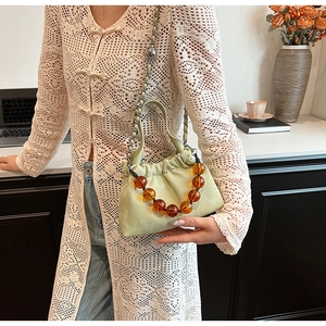 Detail of light green PU handbag with amber beaded handle and metal chain strap