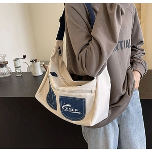 Detail of crossbody bag featuring navy denim pocket with Z SCP logo on canvas