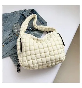 Detail of white quilted bubble shoulder bag with black drawstring on denim jacket background