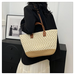 Detail of bohemian woven tote bag showing brown leather handles and dual-tone texture