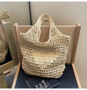Close-up of handmade woven straw tote bag with hollow crochet texture on wooden chair