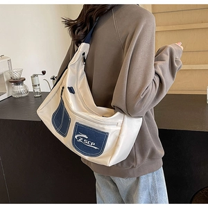 Detailed view of cream canvas crossbody bag with navy pocket and adjustable strap