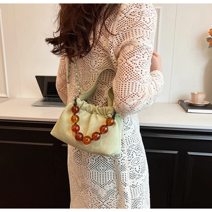 Detail of light green PU drawstring bag with amber beads and silver chain strap